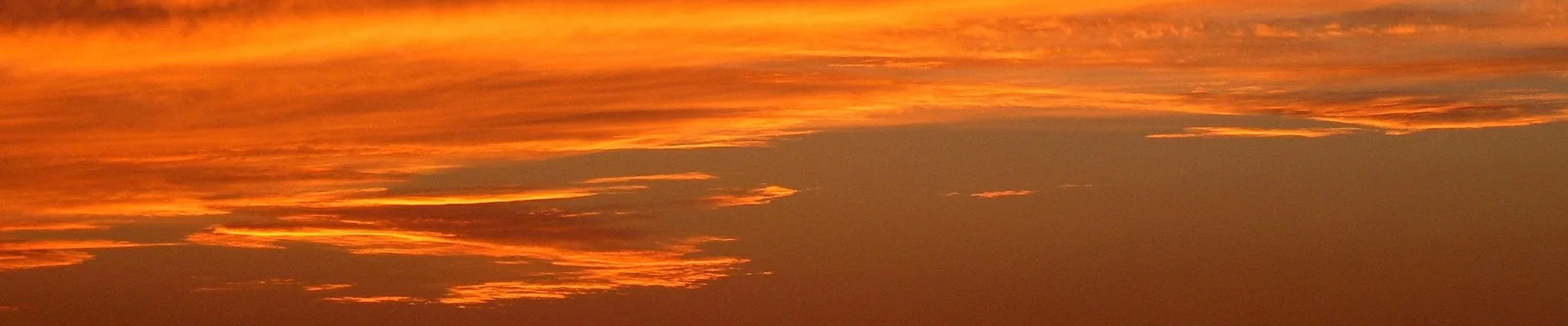 Vibrant orange and golden sunset sky with wispy clouds across the horizon
